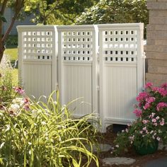 a white fence surrounded by plants and flowers