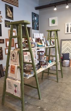 several wooden ladders are on display in a room with pictures and other art work