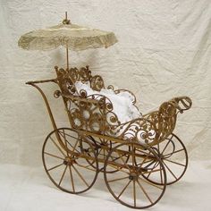 a miniature baby carriage with an umbrella on the top, and white sheets in the back