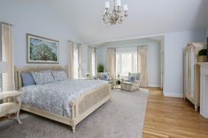 a bedroom with a large bed and chandelier in the corner, along with two chairs