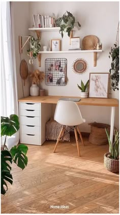 a desk with some plants and pictures on the wall above it in a home office