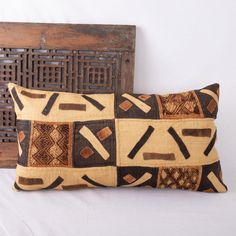 two decorative pillows on a bed next to an old wooden headboard and wall panel