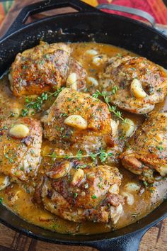 a skillet filled with meat covered in gravy and garnished with herbs