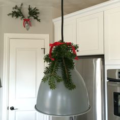 a christmas decoration hanging from the ceiling in a kitchen with white cabinets and silver appliances