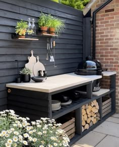 an outdoor bbq with potted plants and pots on the shelf next to it