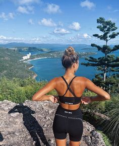 a woman standing on top of a mountain looking at the ocean