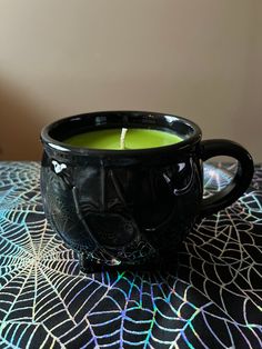 a black cup with a candle in it sitting on a table