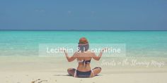 a woman is sitting on the beach with her hands up and looking out at the water