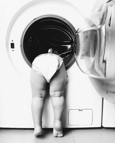 a baby standing in front of a washing machine