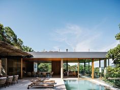 an outdoor swimming pool with lounge chairs and tables next to it, surrounded by greenery