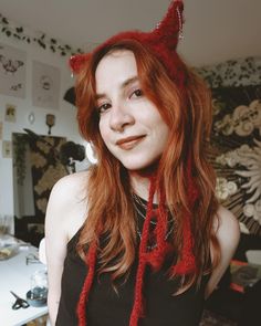 a woman with red hair wearing a knitted cat hat, scarf and black tank top