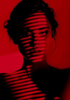 a woman's face is shown through the lines of red and black stripes on her body