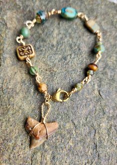 a bracelet with a heart charm and charms on it sitting on top of a rock