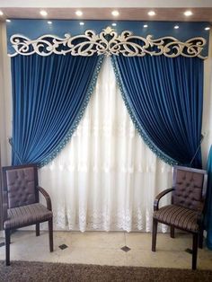 two chairs sitting in front of a window with blue drapes and curtains behind them