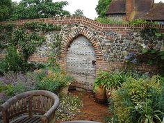 an old brick wall with a wooden door surrounded by flowers