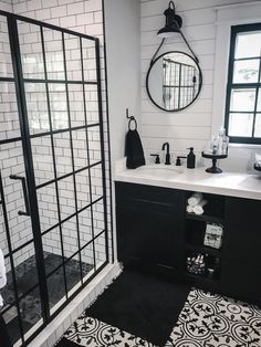 a black and white tiled bathroom with shower, sink, mirror and towel rack on the wall