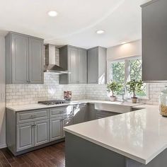 a large kitchen with gray cabinets and white counter tops, along with hardwood floorsing