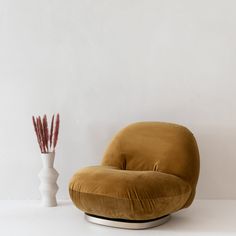 a brown chair next to a white vase