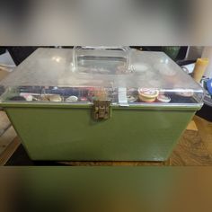 a green box with some food in it on top of a wooden table next to other items