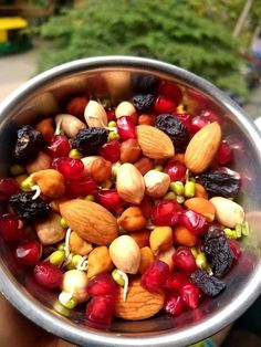 a silver bowl filled with nuts and cranberries