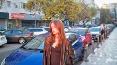 a woman standing next to a row of parked cars