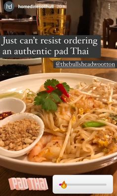 a white plate topped with noodles and sauces next to a glass of beer on top of a wooden table