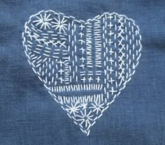 an embroidered heart on a blue piece of cloth with white threadwork in the middle