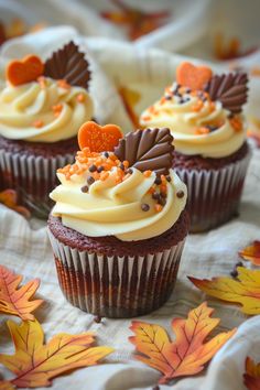 three cupcakes with white frosting and orange sprinkles on top