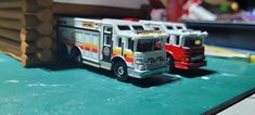 two toy fire trucks sitting on top of a table