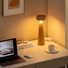 a laptop computer sitting on top of a white desk next to a cup and saucer