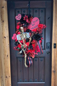 a skeleton wreath on the front door of a house with red flowers and hearts attached to it