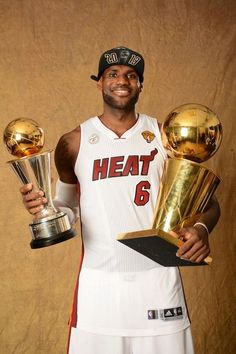 a basketball player holding two trophies in his hands