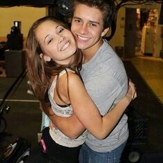 a young man and woman hugging each other in front of a camera on a tripod