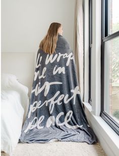 a woman wrapped in a blanket looking out the window