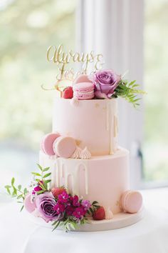 a three tiered cake with pink frosting and flowers