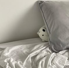 a stuffed animal is peeking out from under the covers on a bed with white sheets