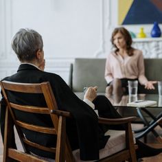 two women sitting at a table talking to each other and one woman standing in the background