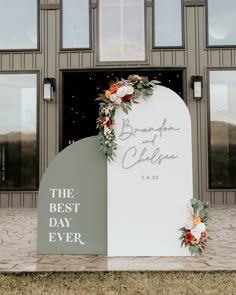 a sign that says the best day ever with flowers on it in front of a building