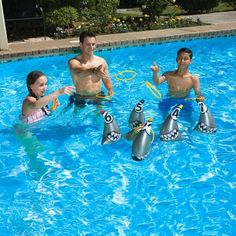 three children and an adult playing in a pool with water toys while two adults watch