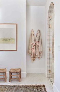 a bathroom with two towels hanging on the wall and stools in front of it