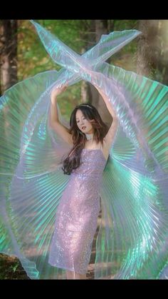 a woman in a purple dress is posing with her arms behind her head and hands on her hips