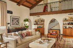 a living room filled with furniture and lots of wood flooring next to a stair case