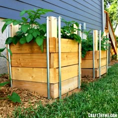 a row of wooden planters with plants growing in them on the side of a house