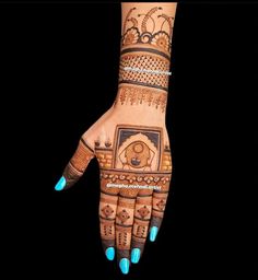 a woman's hand with henna tattoos and blue nail polishes on it