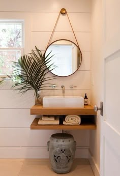 a bathroom with a sink, mirror and potted palm tree in the corner next to it