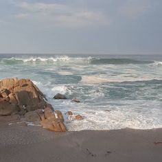 an ocean view with waves crashing on the rocks