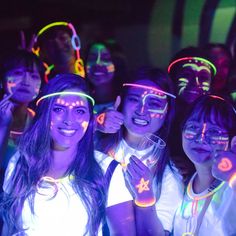 a group of young people standing next to each other with neon lights on their faces