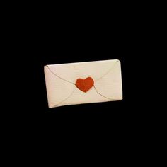 a white envelope with a red heart on the front and back flap, against a black background