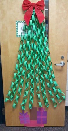 a christmas tree made out of green paper and red ribbon on a door with the words happy holidays written on it