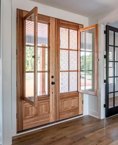 an empty room with two double doors and wood trimming on the windows, along with hardwood flooring